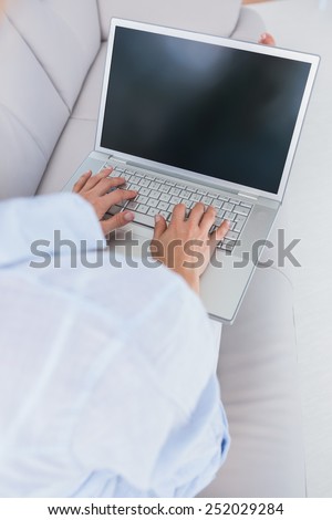 Woman on couch typing on laptop at home in the living room