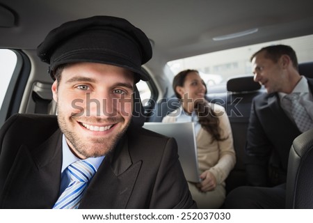 Handsome chauffeur smiling at camera in the car