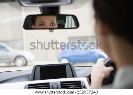 Woman driving with her reflection in the mirror in her car