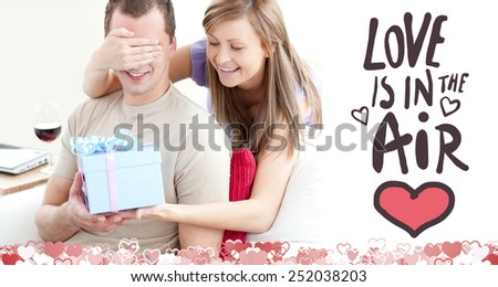 Smiling woman giving a present to her boyfriend against love is in the air