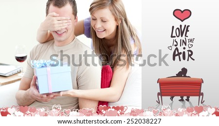 Smiling woman giving a present to her boyfriend against love is in the air