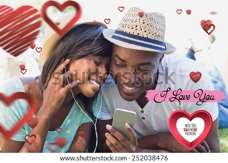 Happy couple lying in garden together listening to music against cute valentines message