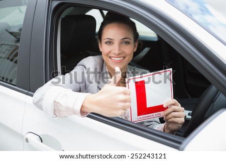 Female driver giving thumbs up while holding her L sign in her car