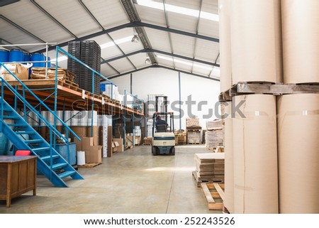 Forklift amid rows of boxes in a large warehouse