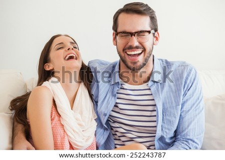 Young couple smiling at camera on couch at home in the living room