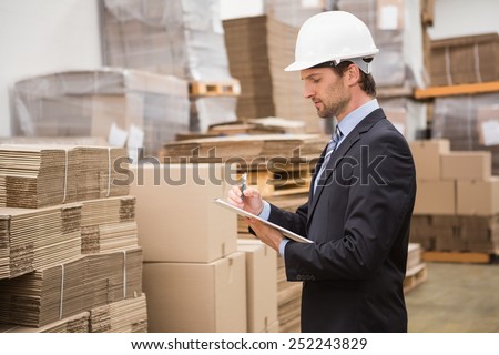 Serious warehouse manager checking inventory in warehouse