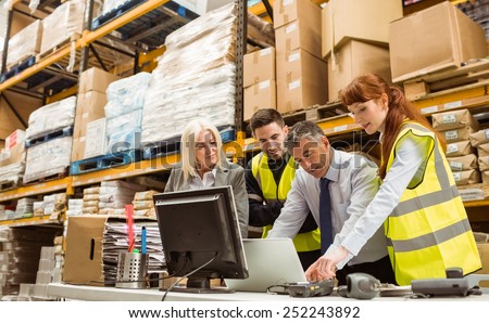 Warehouse managers and worker talking in a large warehouse