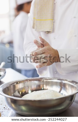Baker clapping flour from his hands in the kitchen of the bakery