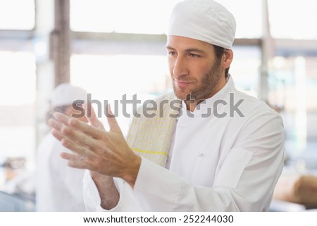 Baker clapping flour from his hands in the kitchen of the bakery