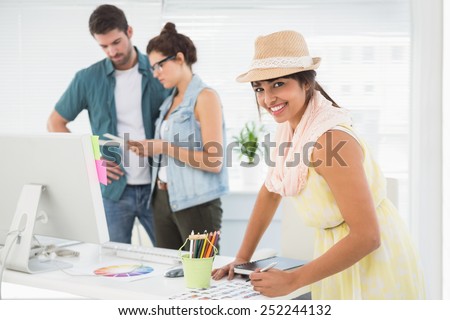 Smiling designer in front of colleagues using colour wheel in the office