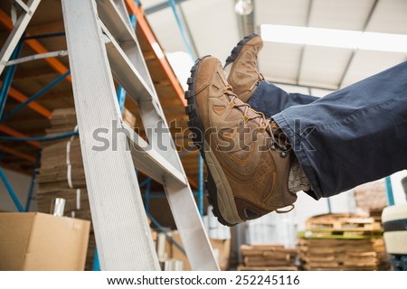 Low section of worker falling off ladder in the warehouse