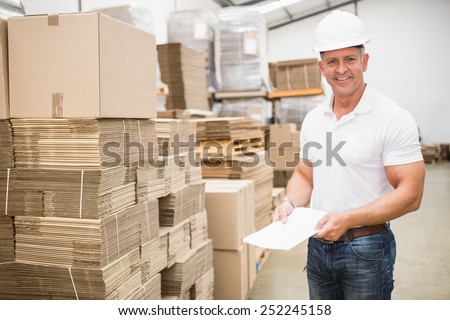 Smiling warehouse worker with clipboard in warehouse