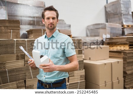Warehouse worker carrying a small box in a large warehouse