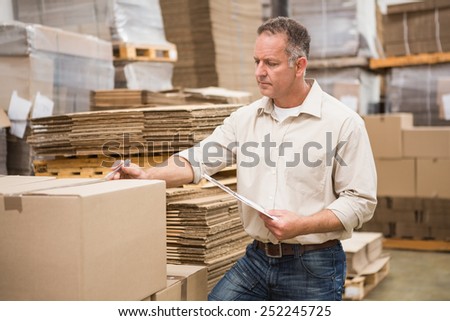 Warehouse worker checking his list on clipboard in a large warehouse