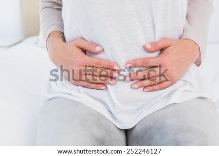 Mid section of woman with stomach pain in hotel room