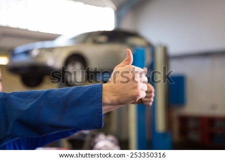 Team of mechanics giving thumbs up at the repair garage