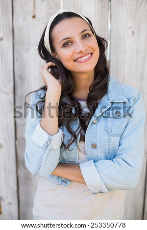 Pretty hipster smiling at camera against bleached wooden fence