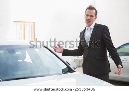 Businessman looking his car engine after breaking down in a car park