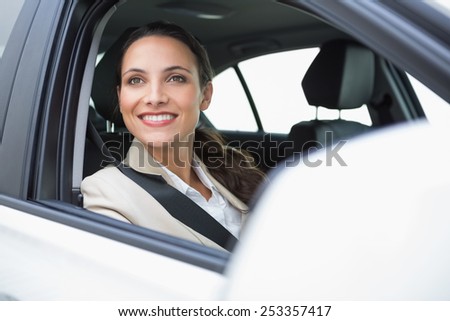Smiling businesswoman looking out the window in her car