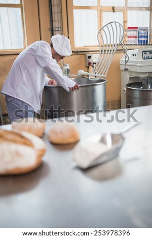 Baker preparing dough in industrial mixer at the bakery