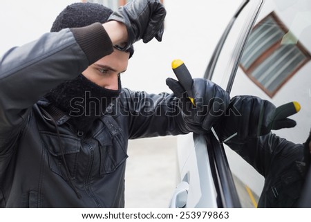 Thief breaking into a car in broad daylight