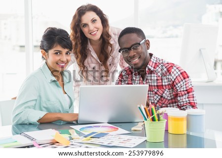 Smiling teamwork with laptop looking at camera in the office