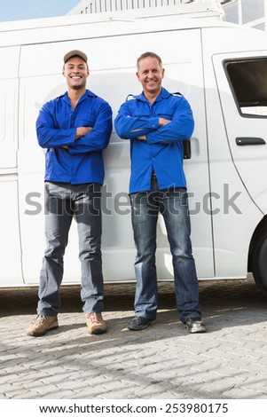 Smiling handymen looking at camera in front of their van