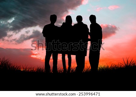 Silhouette of team holding a poster against red sky over grass