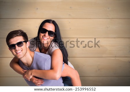 Man giving his pretty girlfriend a piggy back against bleached wooden planks background