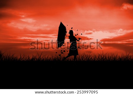 Silhouette of woman holding broken umbrella with leaves blowing against red sky over grass