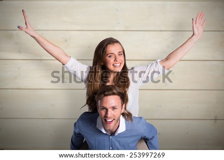 Smiling young man carrying woman against bleached wooden planks background