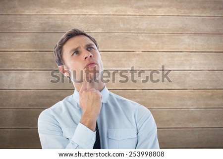 Thinking businessman with finger on chin against wooden surface with planks