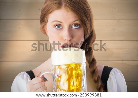 Oktoberfest girl drinking jug of beer against bleached wooden planks background