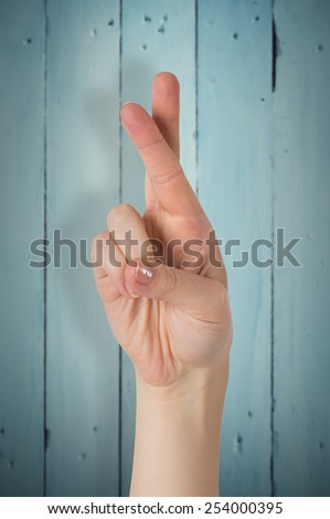Hand with fingers crossed against painted blue wooden planks