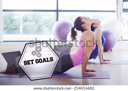 The word set goals and fit women doing the cobra pose in fitness studio against hexagon
