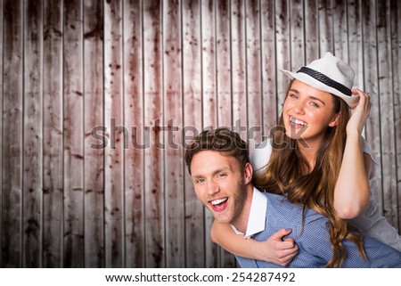 Smiling young man carrying woman against wooden planks