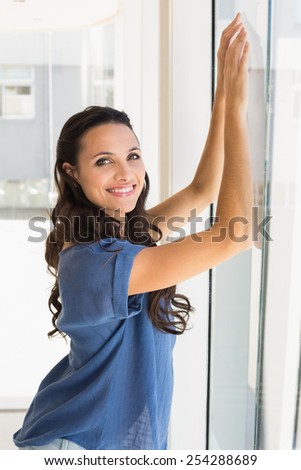 Pretty brunette smiling at camera at home beside window