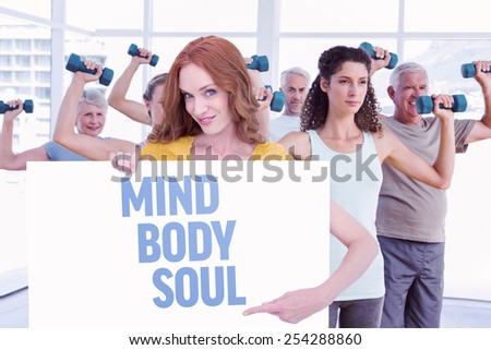 Pretty redhead showing a poster against mind body soul