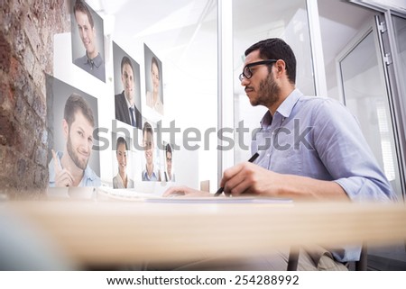 Man working at desk with computer and digitizer against profile pictures
