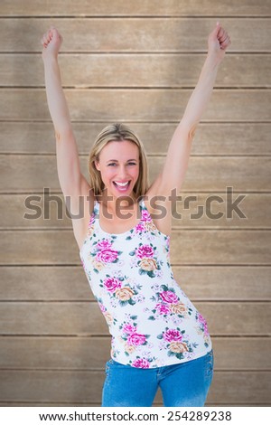 Happy blonde cheering with arms up against wooden planks