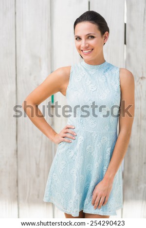 Stylish brunette smiling at camera against bleached wooden fence