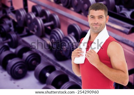 Fit man smiling at camera against collection of barbells