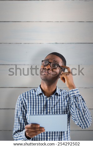 Young businessman thinking and holding tablet against wooden planks
