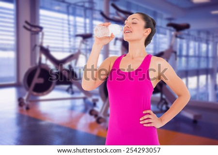 Fit woman taking a drink against spin bikes in fitness studio