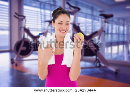 Fit woman smiling at camera against spin bikes in fitness studio