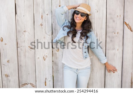 Pretty hipster smiling at camera against bleached wooden fence