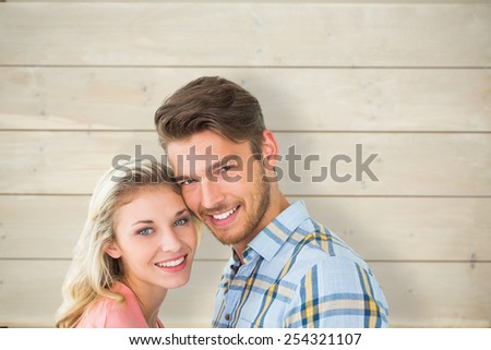Attractive couple smiling at camera against bleached wooden planks background