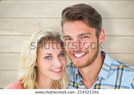 Attractive young couple smiling at camera against bleached wooden planks background