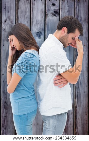 Upset couple not talking to each other after fight against grey wooden planks