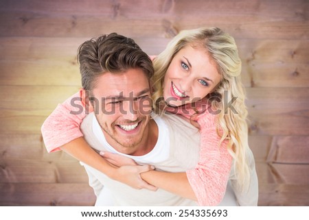 Handsome man giving piggy back to his girlfriend against wooden planks